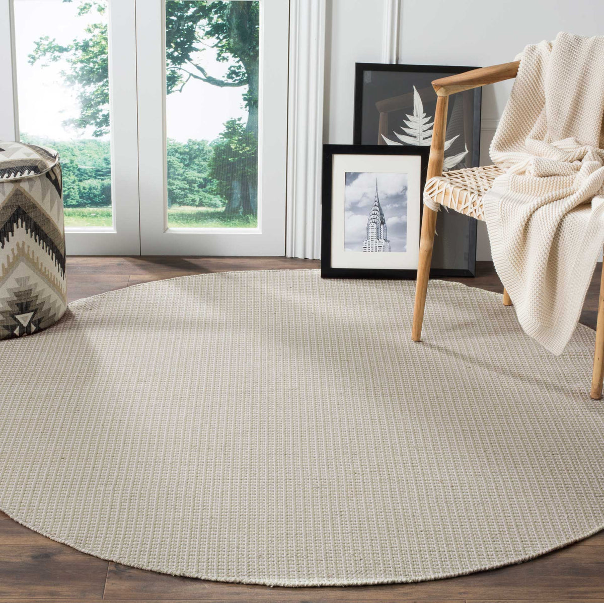 Soft ivory and green round rug adds quiet woven texture beneath a reading chair
