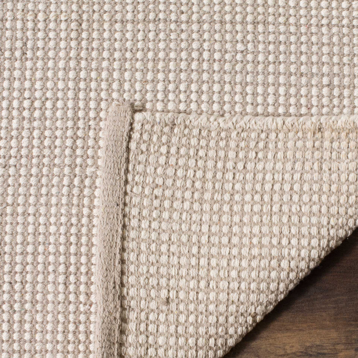 The folded edge shows a dense cotton backing with muted ivory and gray checks.
