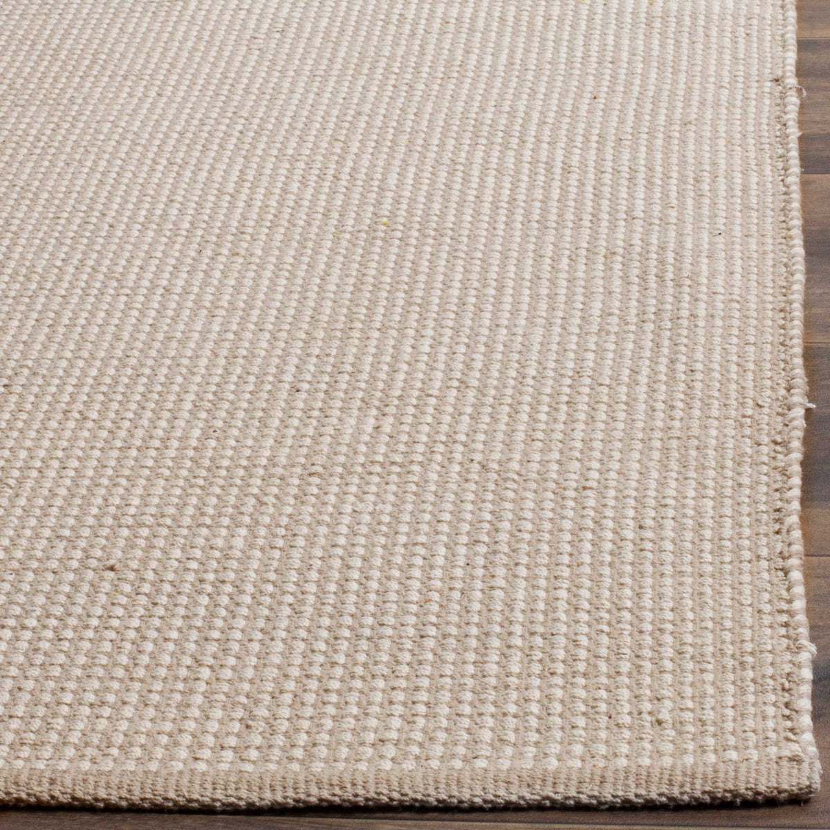 Tiny ivory cotton loops stand out in the gray weave above a neat rug edge.