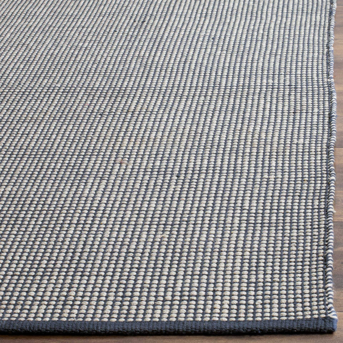 Ivory cotton loops and navy yarns give this rug a richly woven, dark-bound corner.
