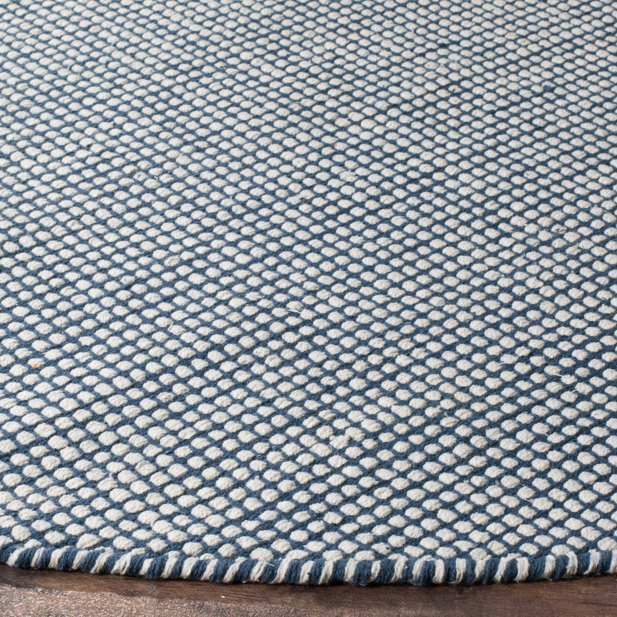 Ivory loops contrast with navy yarns in a textured weave finished with a bound edge.