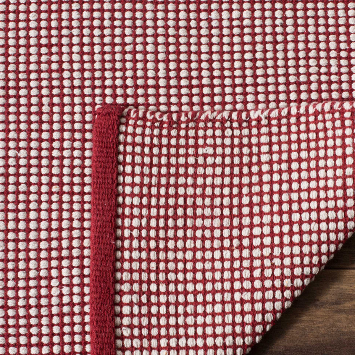 A turned corner shows matching red and ivory checks on the underside and solid red binding.