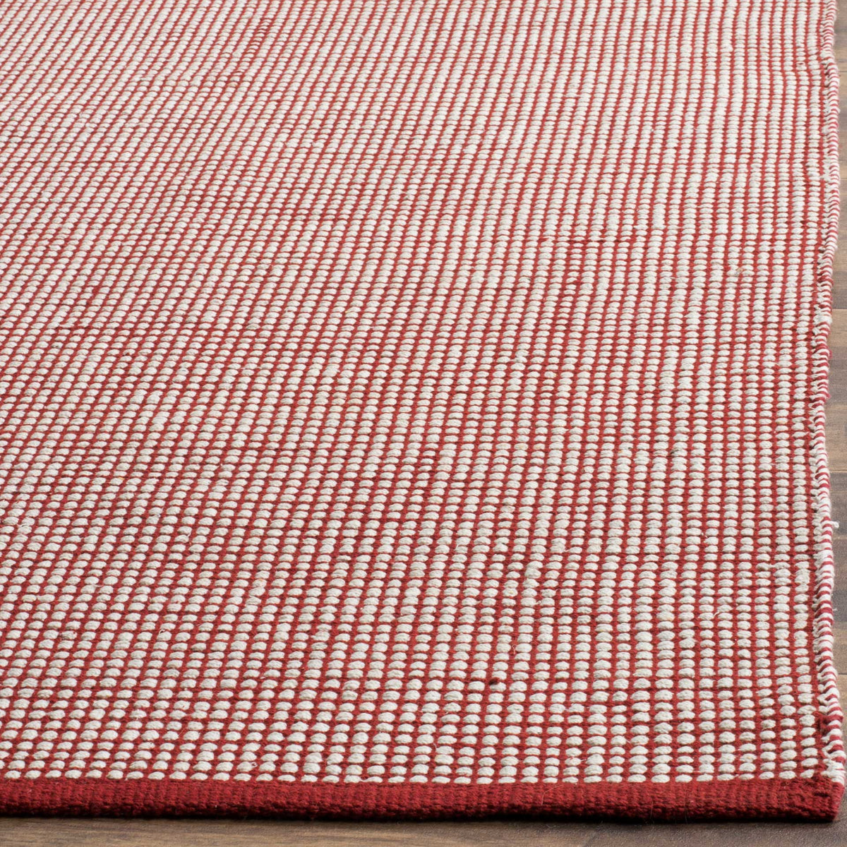 Small ivory cotton loops form a crisp check texture against deep red yarns and trim.