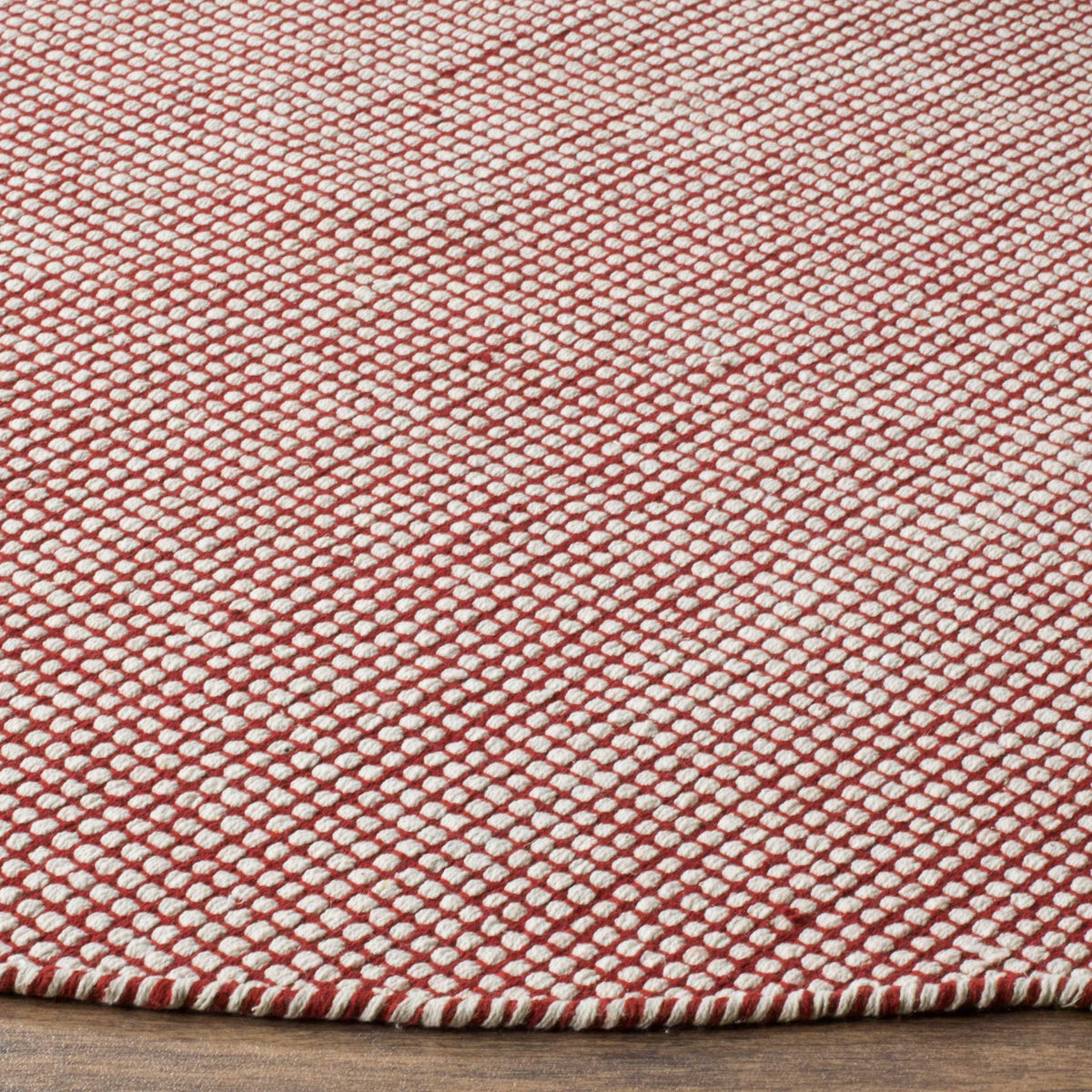 Red and ivory yarns create a textured weave framed by a neat, striped edge.