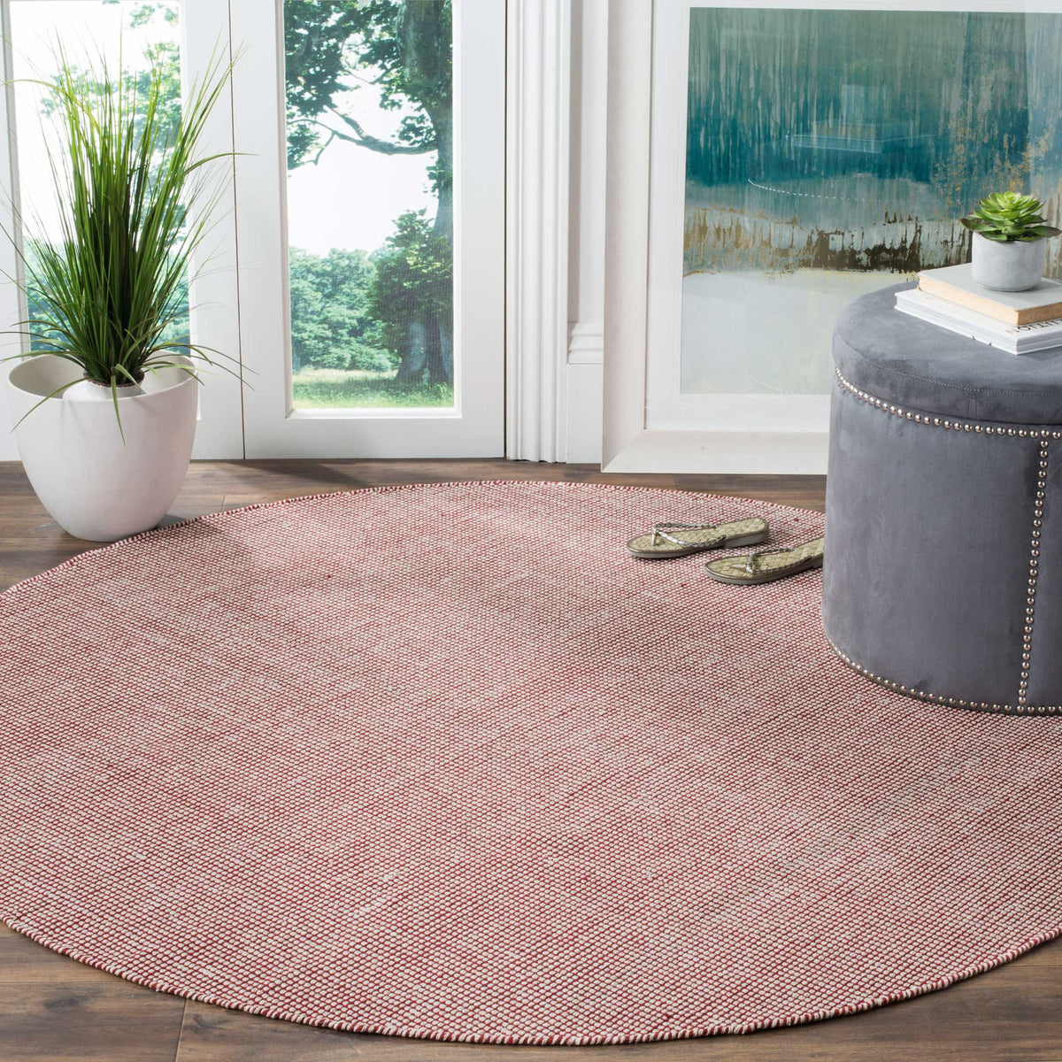 An ivory and red round rug adds warmth and a relaxed woven feel to a cozy seating area.