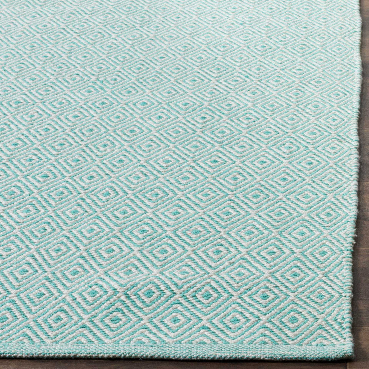 Fine aqua diamonds and a slim woven border add texture to this cotton area rug