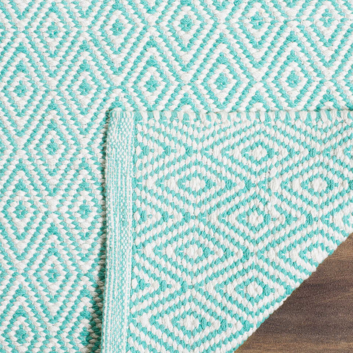 The lifted rug corner shows its woven underside and aqua-edged finish
