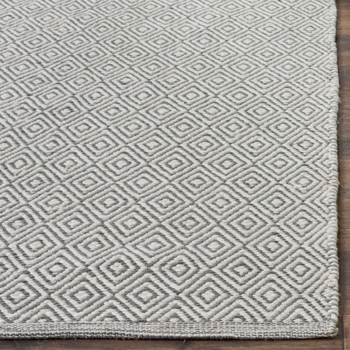 Gray diamonds stand out against ivory cotton beside a tightly finished rug edge
