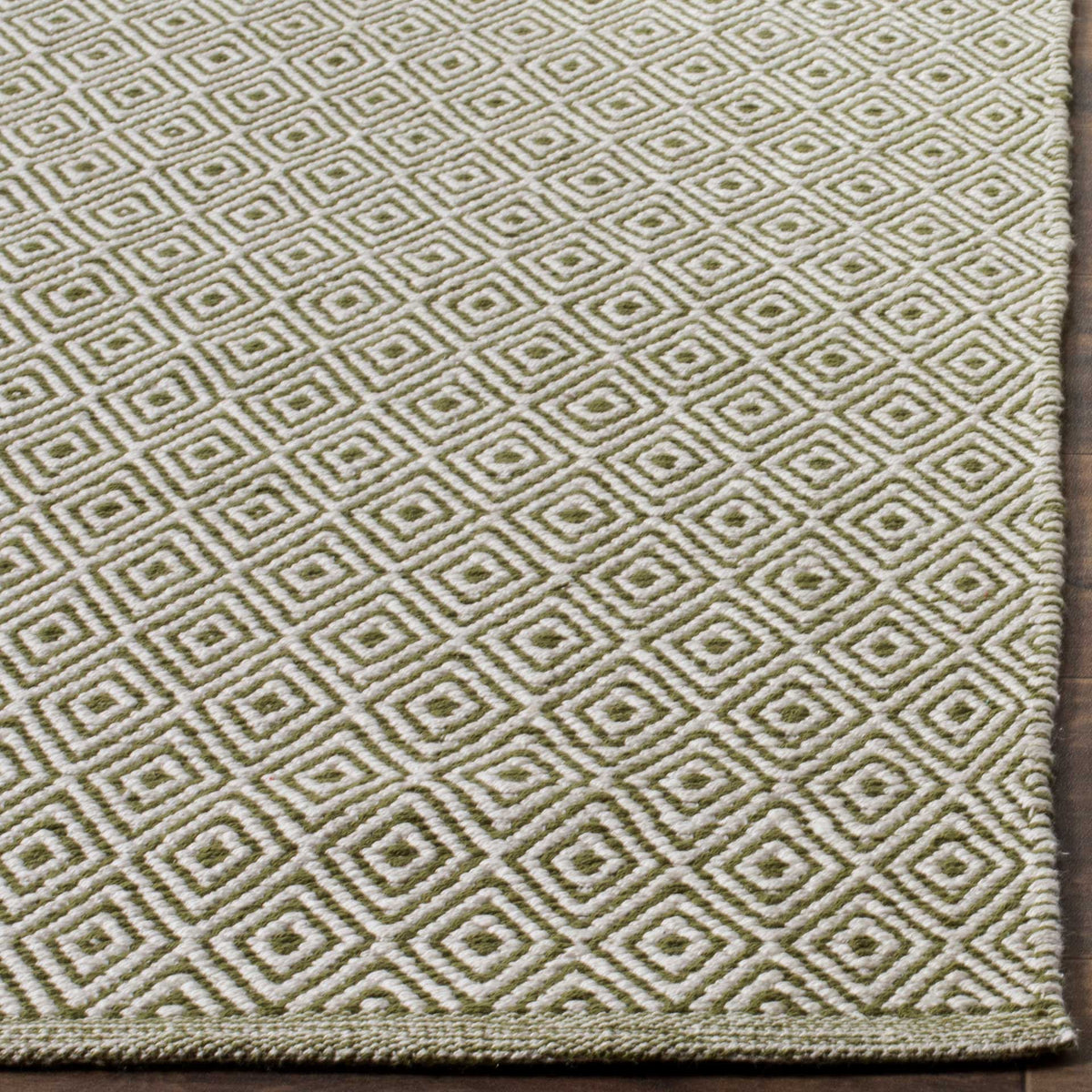 Green and ivory nested diamonds lead to a neatly finished edge on this woven rug