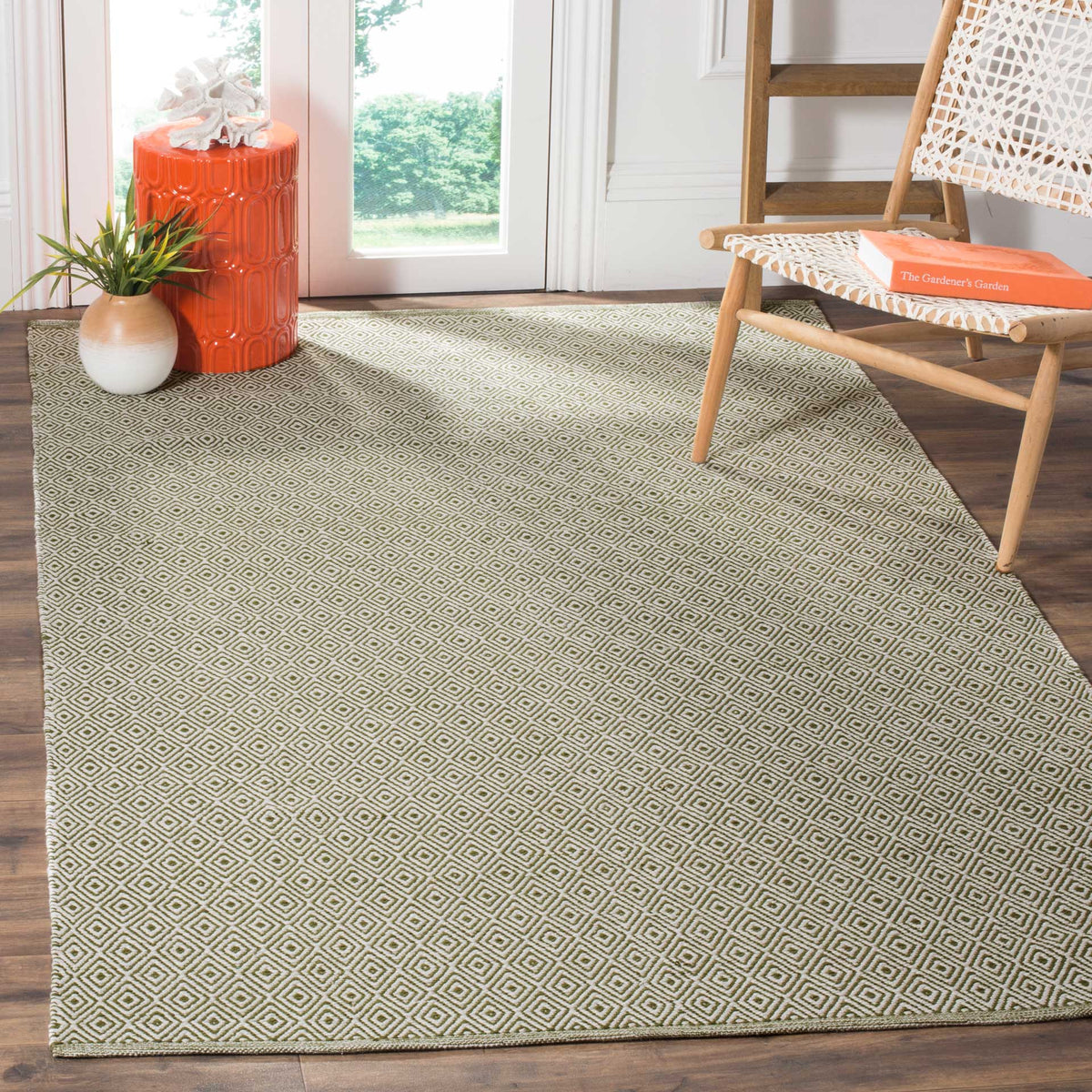 An ivory and green geometric rug grounds a sunny corner with natural color