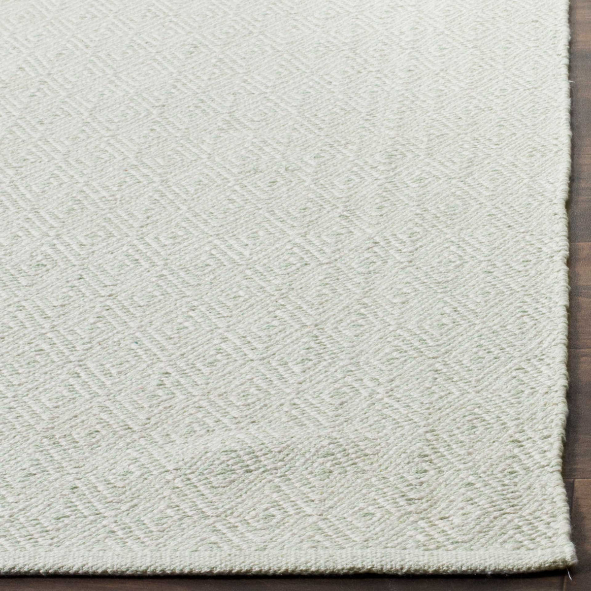Finely woven foam green and ivory texture finishes at a slim rug edge