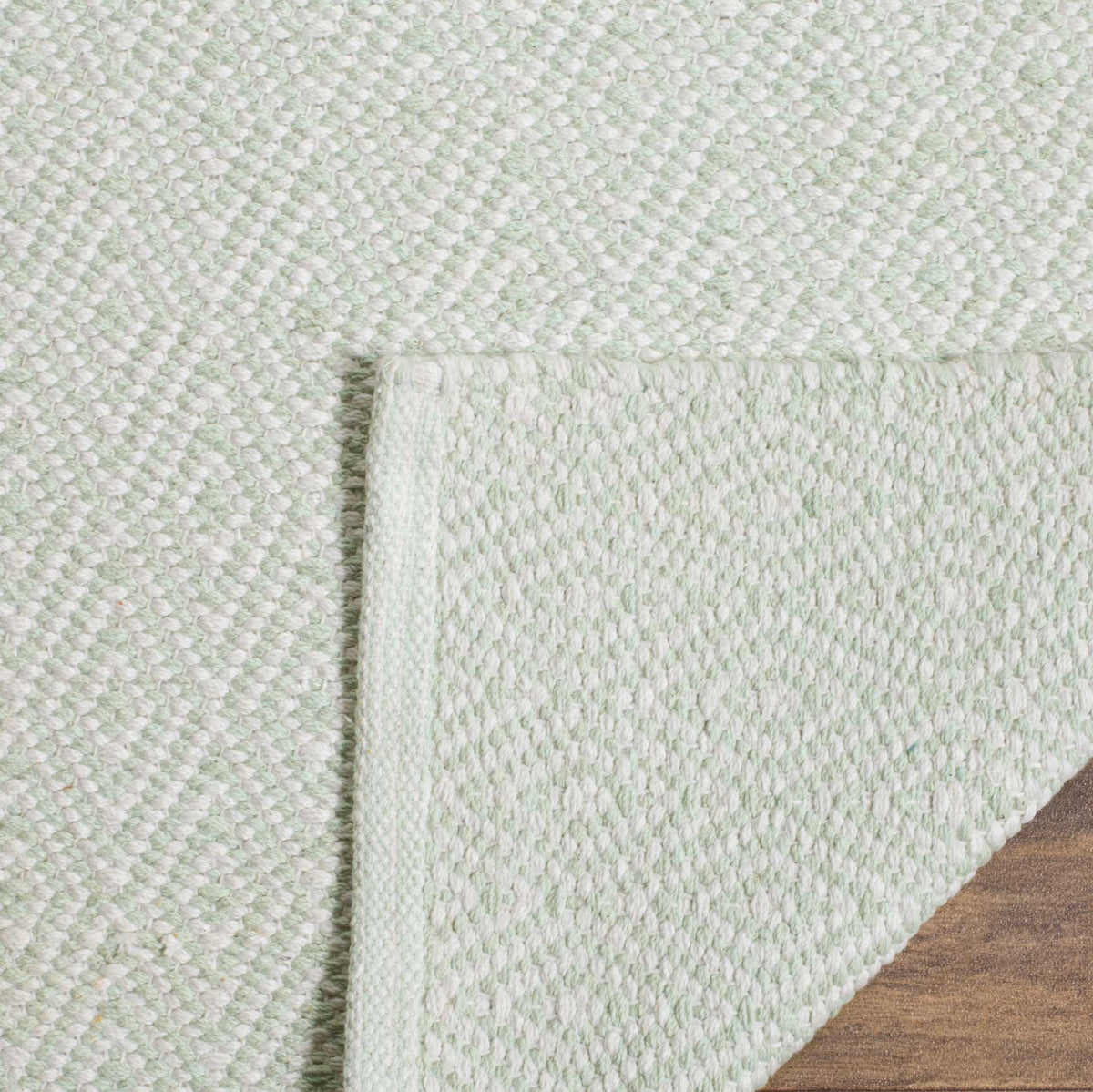 Folded cotton corner reveals a soft ivory and foam green woven underside