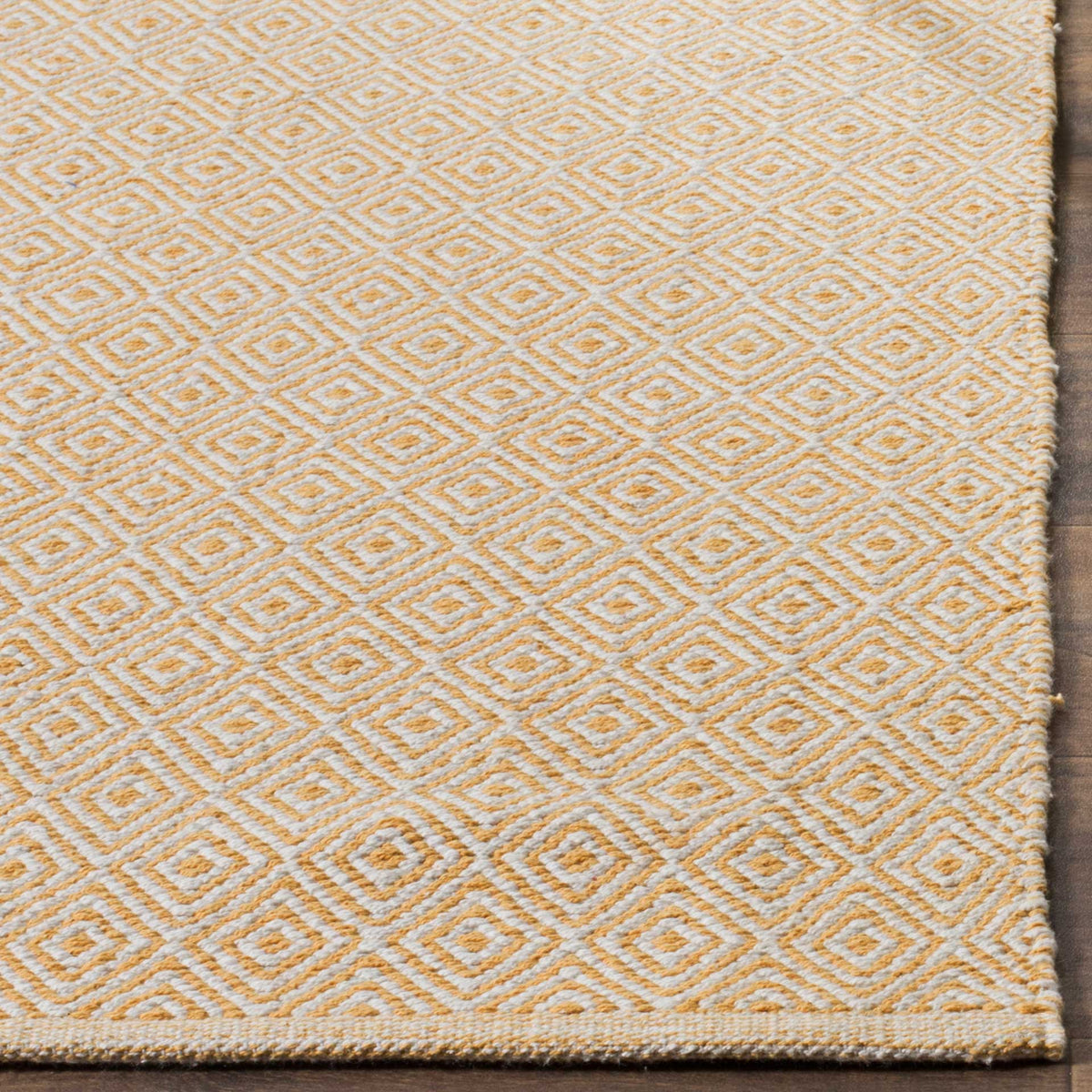Gold and ivory woven diamonds meet a closely finished edge on this cotton rug