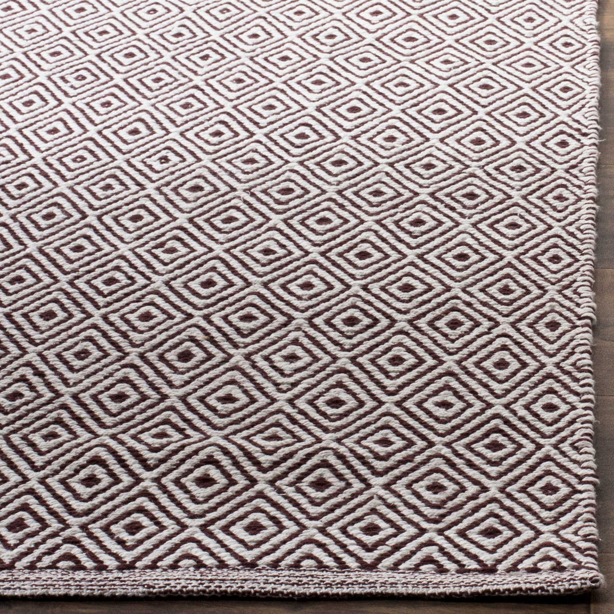 Chocolate and ivory woven diamonds meet a slim finished edge on this cotton rug