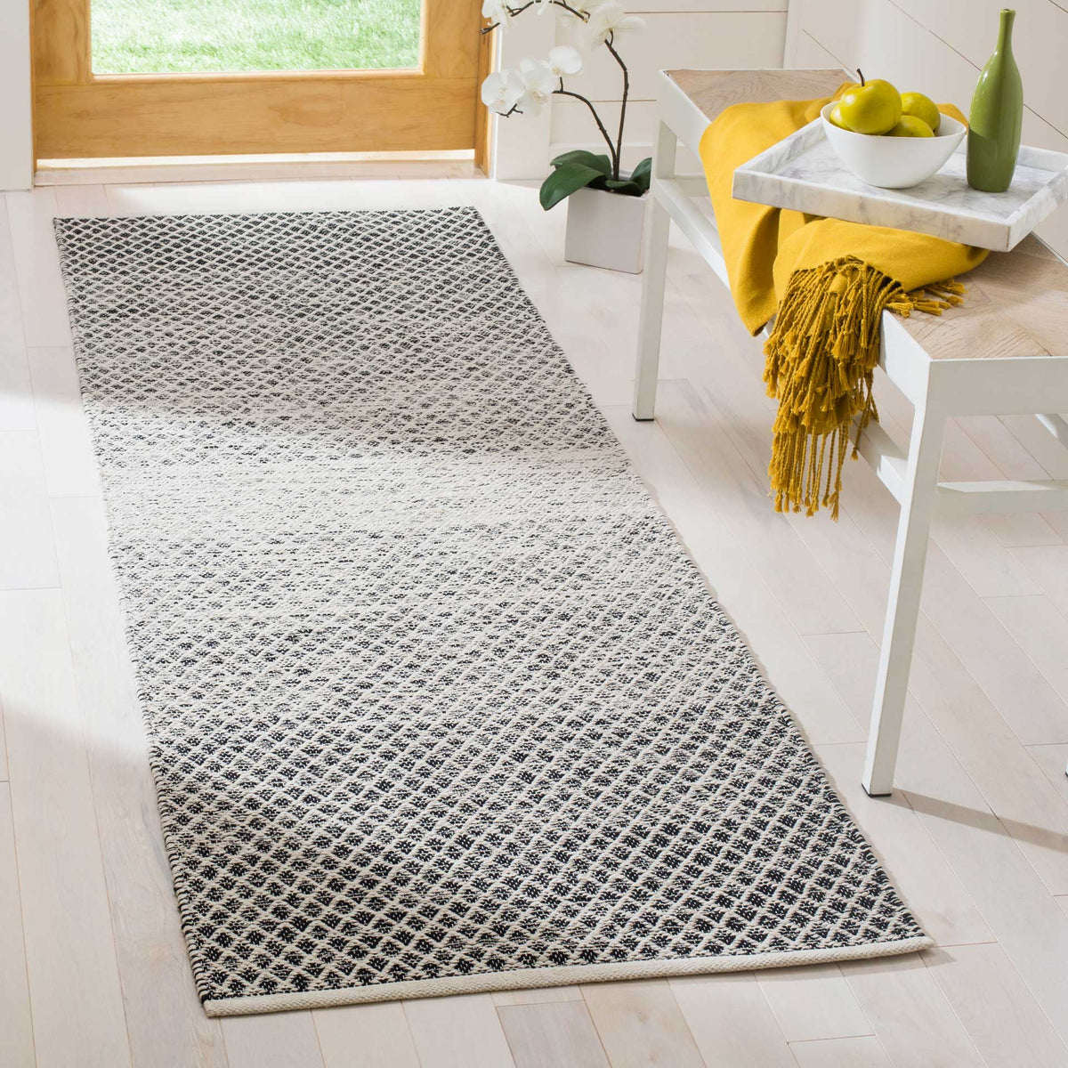 Bold black and ivory lattice runner adds patterned contrast beside a bright entryway bench
