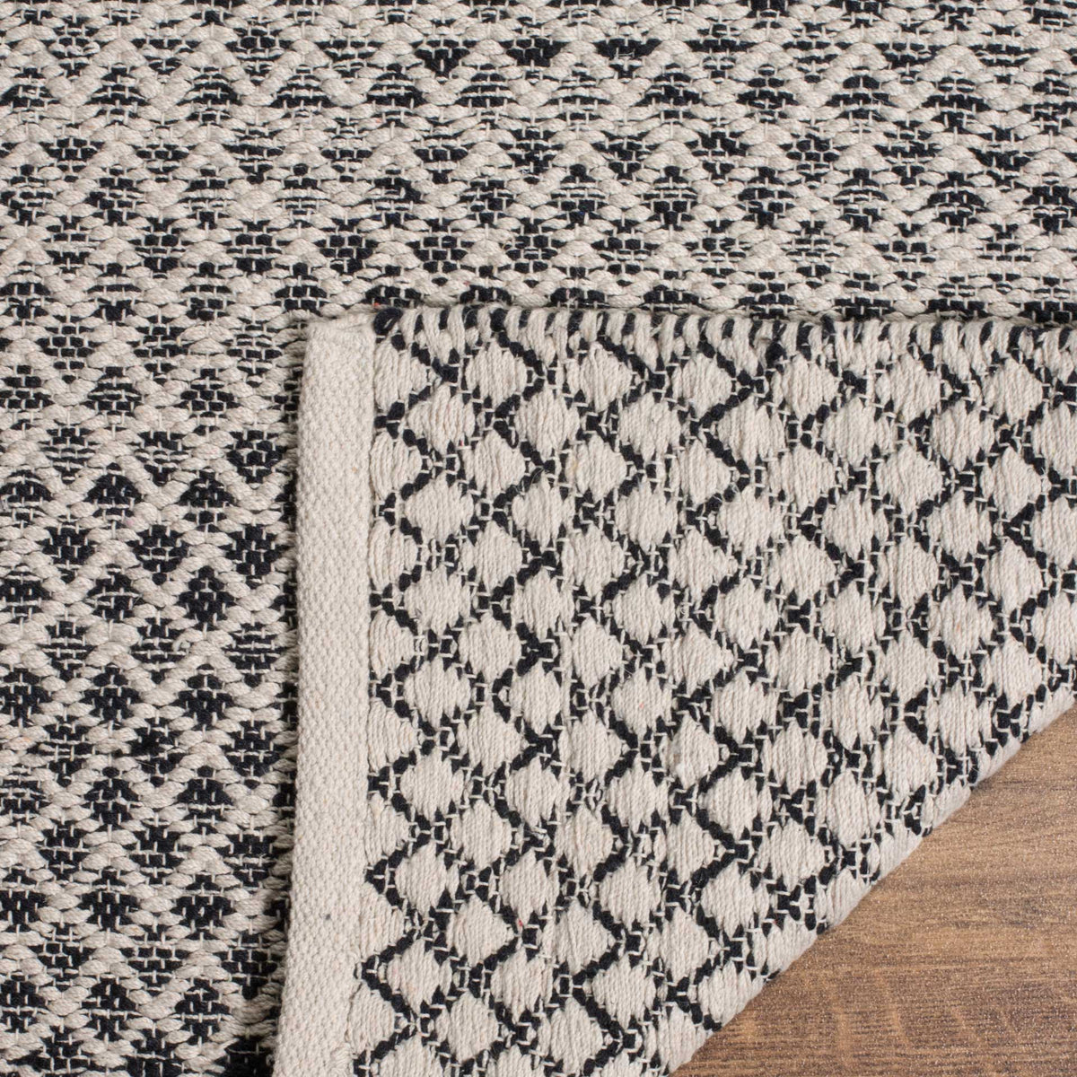 The folded corner reveals a black and ivory woven underside beneath a finished ivory edge.