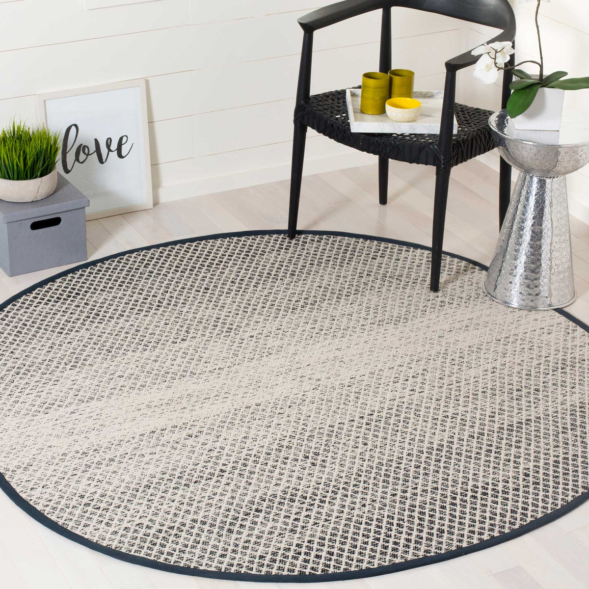 Black and ivory round rug adds a bold geometric foundation beneath a chair