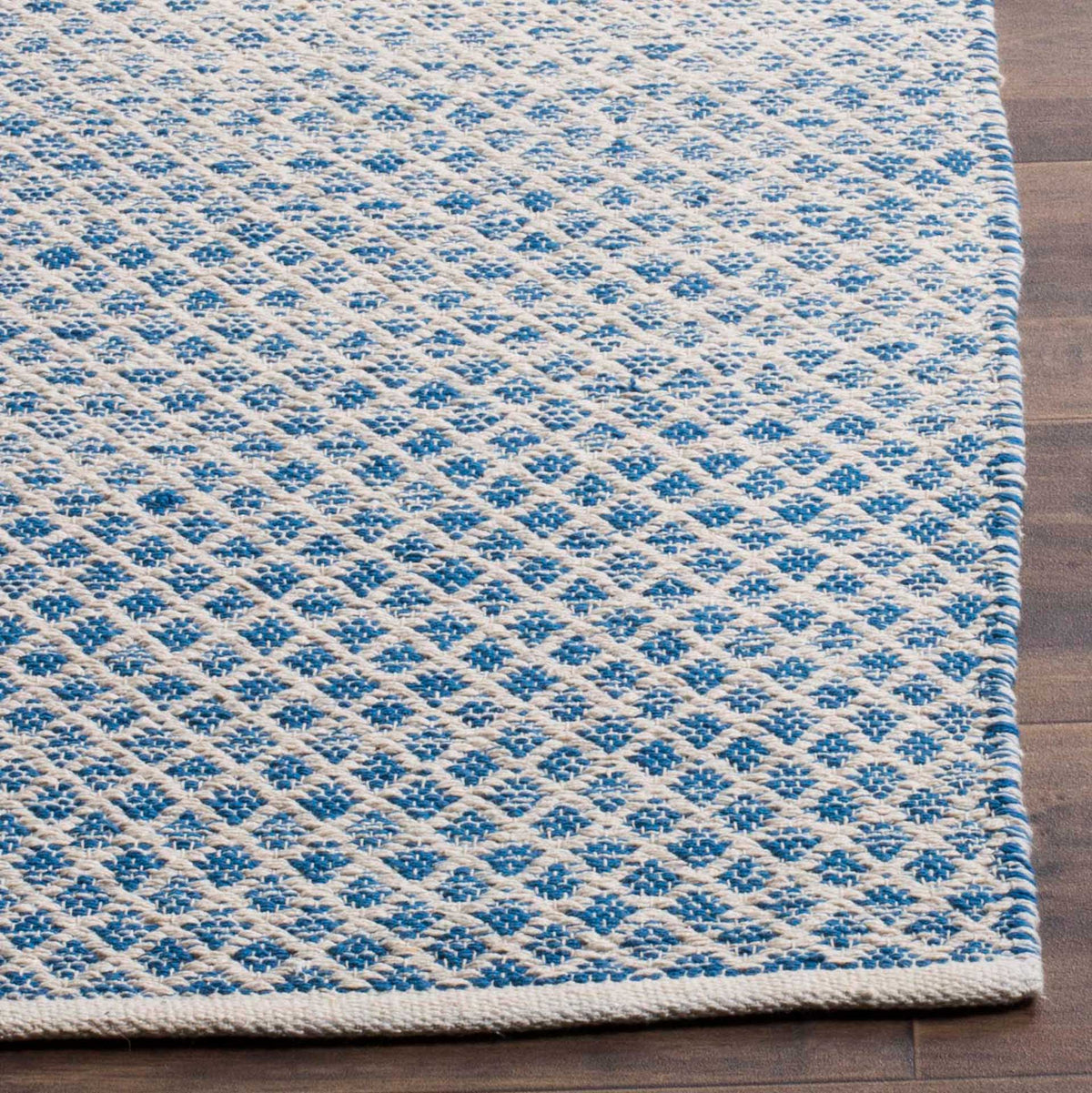 Blue diamond motifs and ivory crosshatching give the cotton rug richly textured edges.