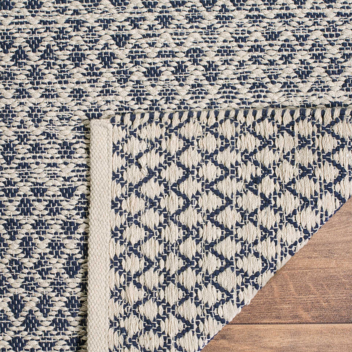 A folded corner reveals the navy and ivory underside and finished cotton edging.