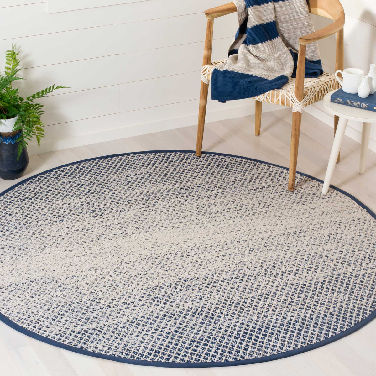 Navy and ivory round rug anchors a seating area with a gently faded geometric weave