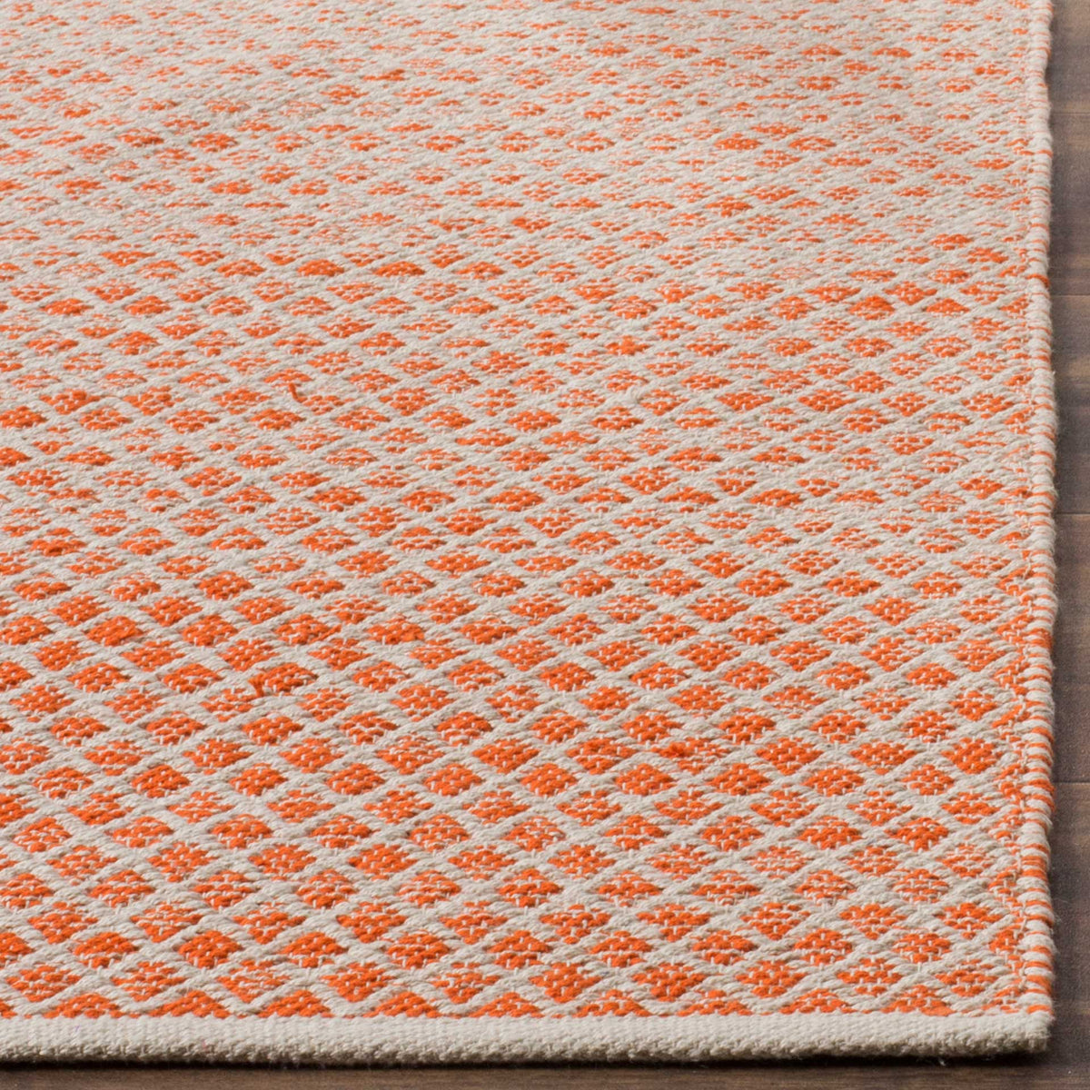 Bright orange diamonds meet ivory cotton along a neatly finished, textured edge.