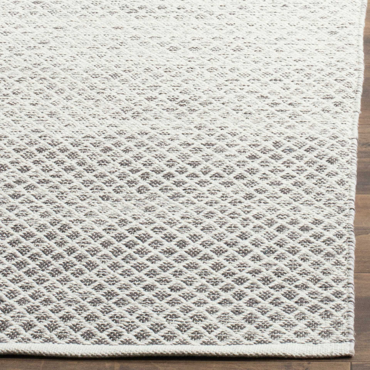 Gray diamond motifs emerge from ivory woven cotton beside a cleanly bound edge.