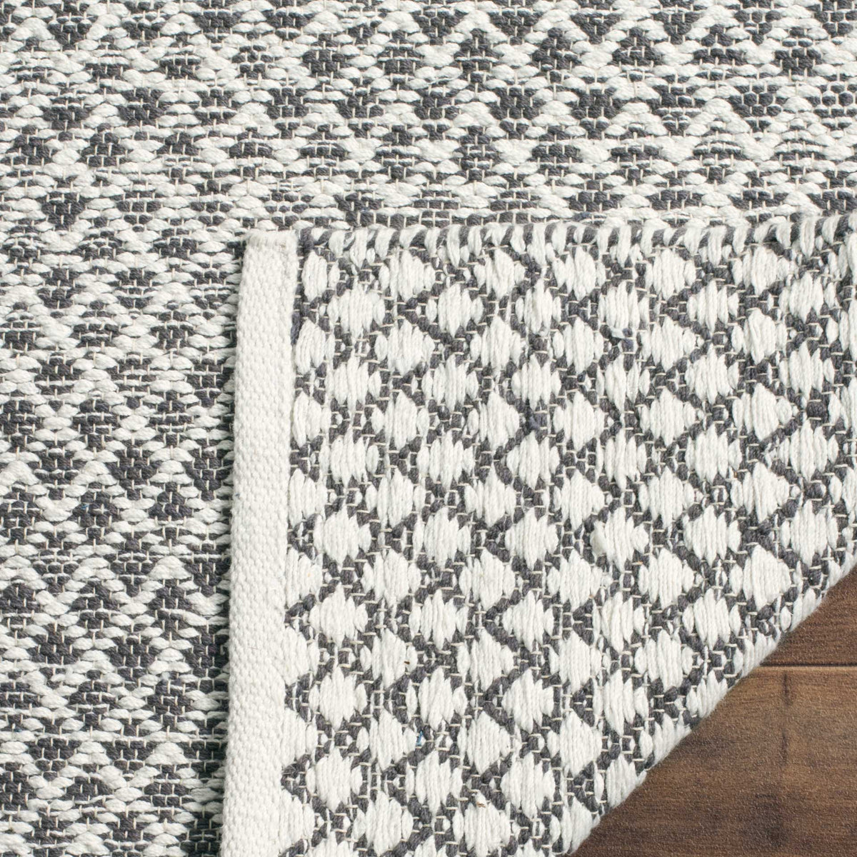 Folded fabric reveals the gray and ivory woven underside and its finished edging.