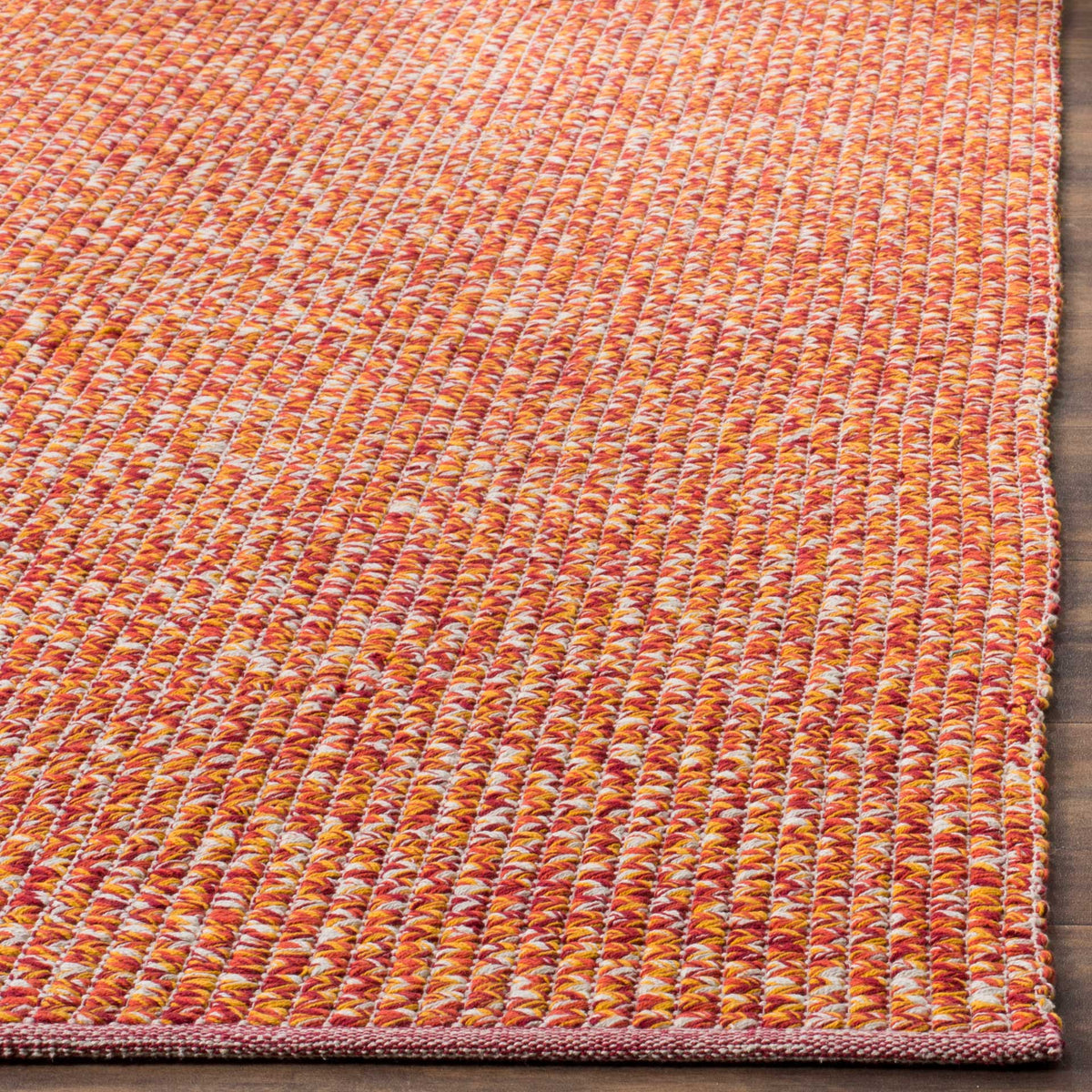 Bright orange, pink, and golden yarns meet at the rug's neatly finished corner
