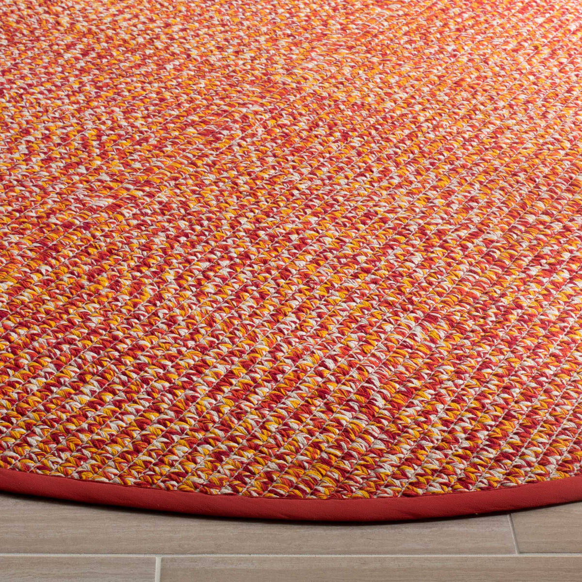 Dense multicolored cotton weave creates lively texture framed by smooth red binding.