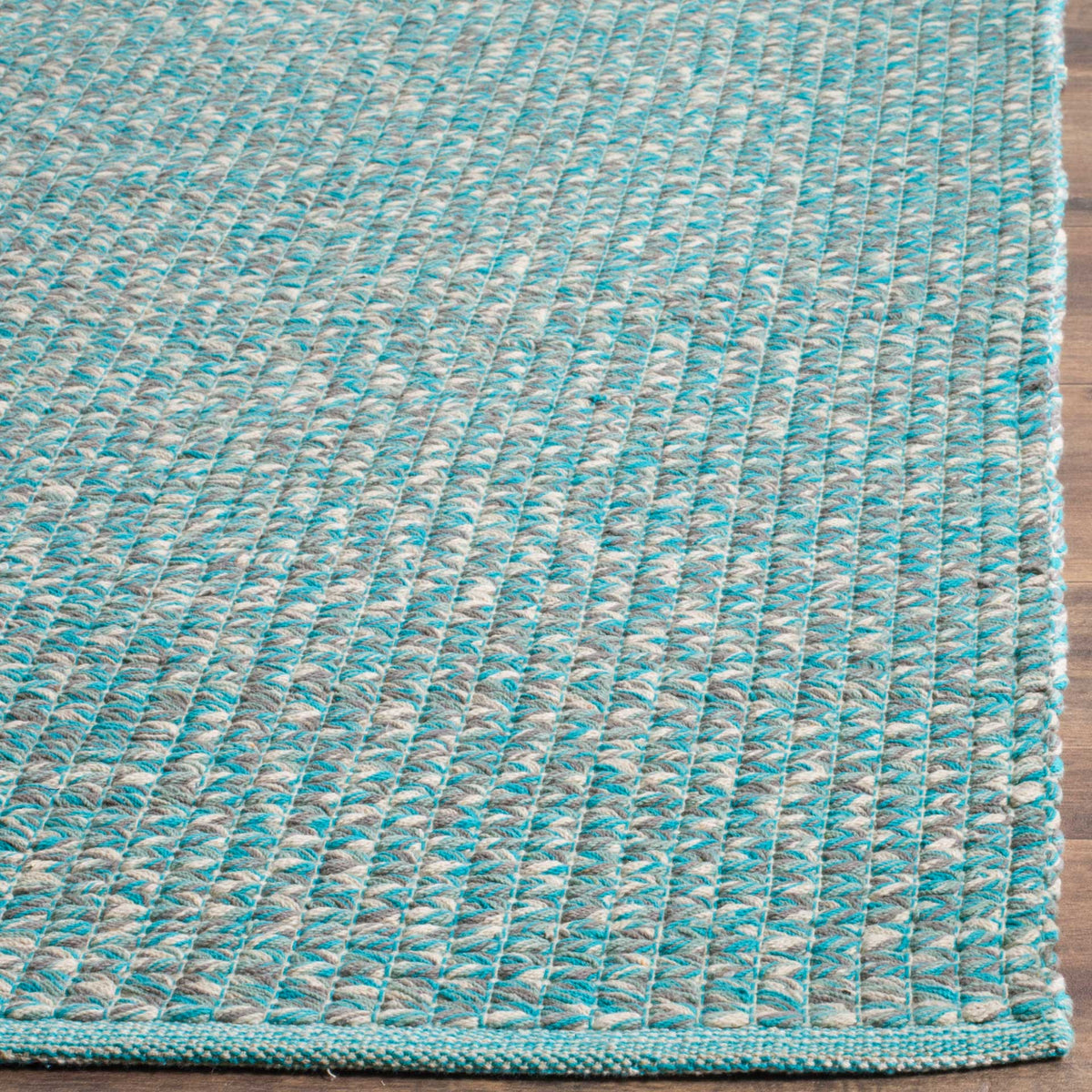 Pale and turquoise cotton threads reveal a tactile weave and finished rug corner