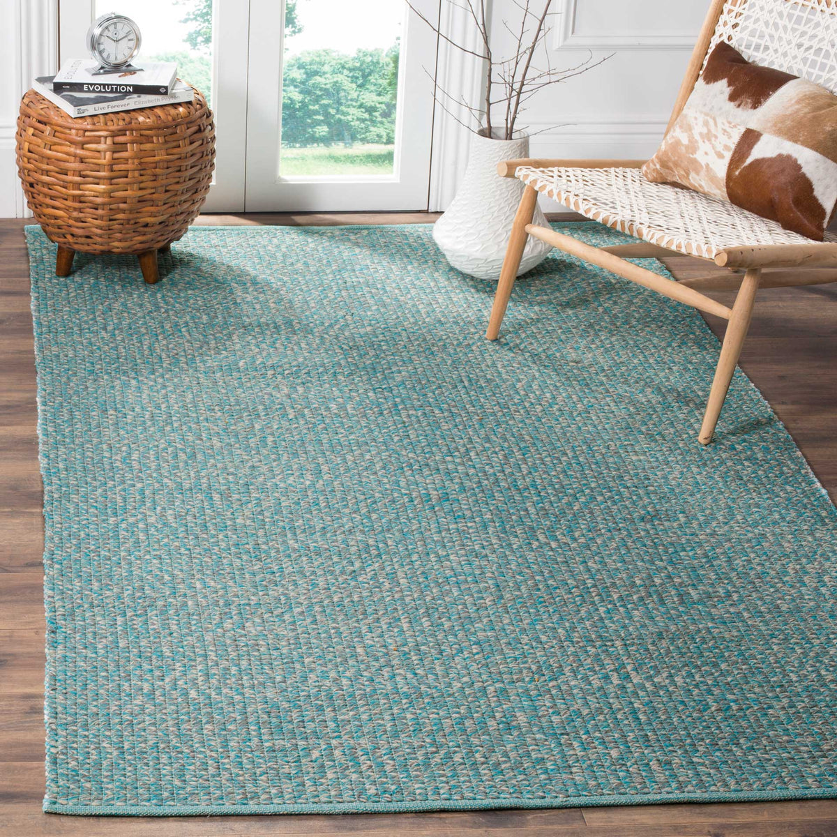 Turquoise woven rug adds color beneath a woven chair and wicker accent table