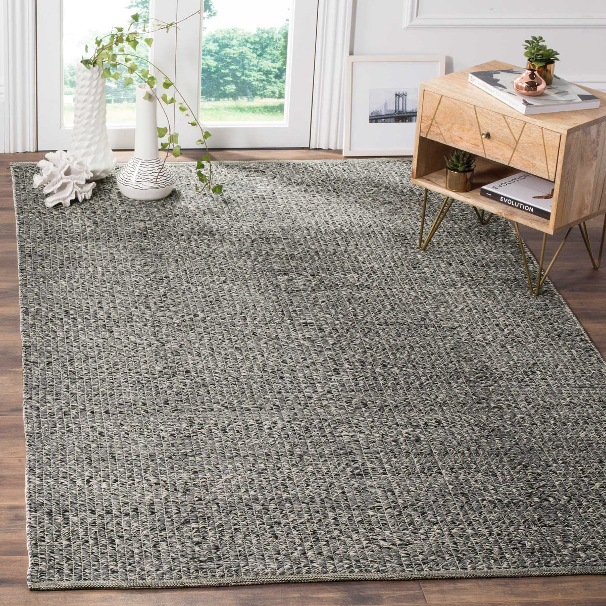 Heathered gray area rug adds woven texture beneath a light wood accent table