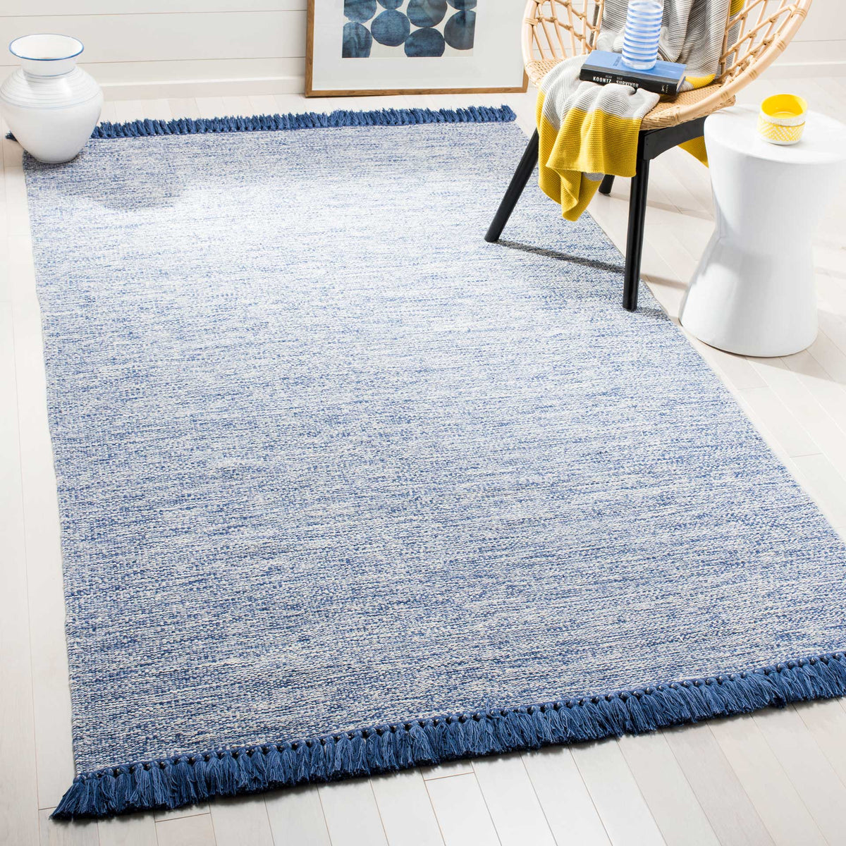 A blue-and-white textured rug brings a calm coastal feel to the floor, with bold fringe at each end.