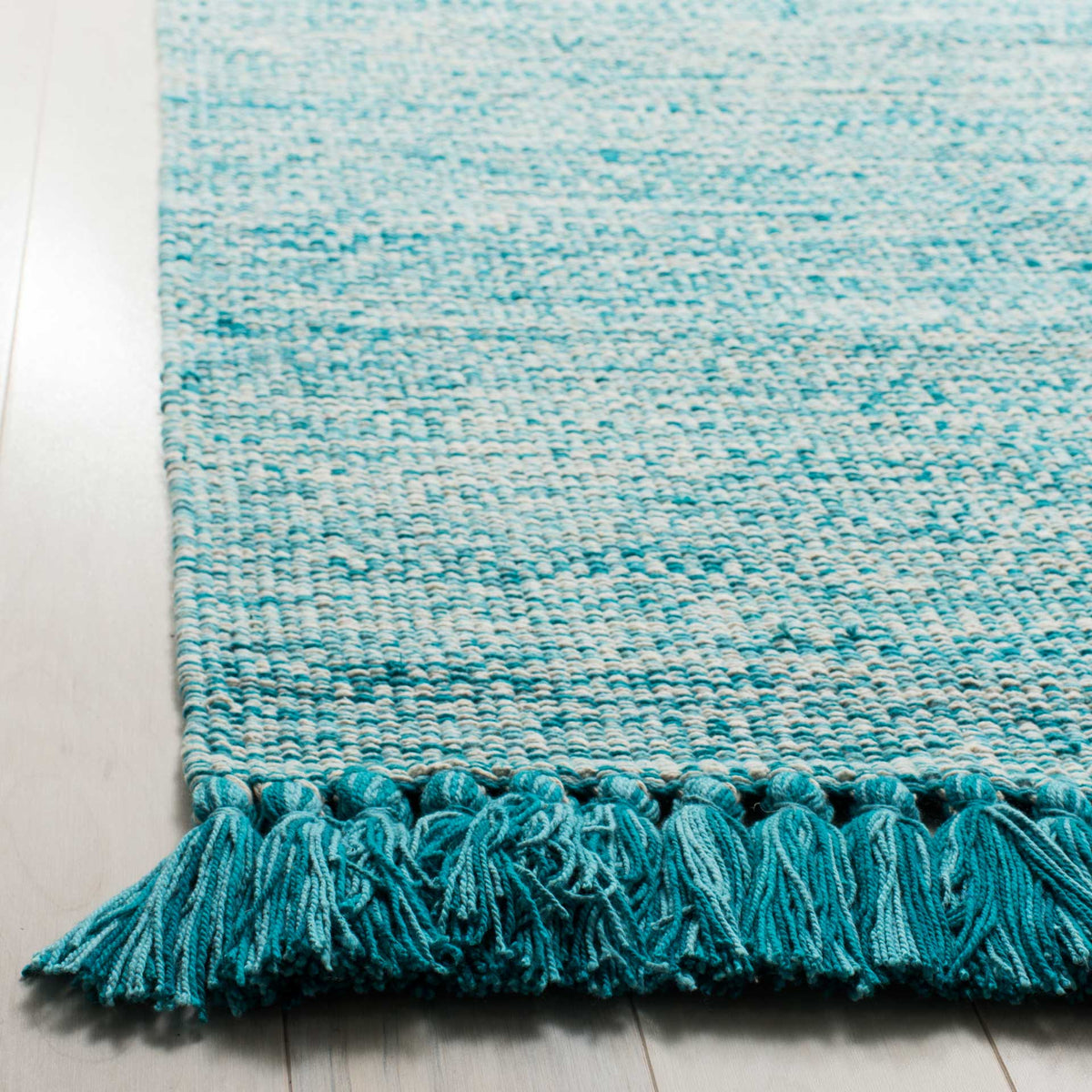Full turquoise tassels accent the rug's speckled aqua-and-ivory weave.