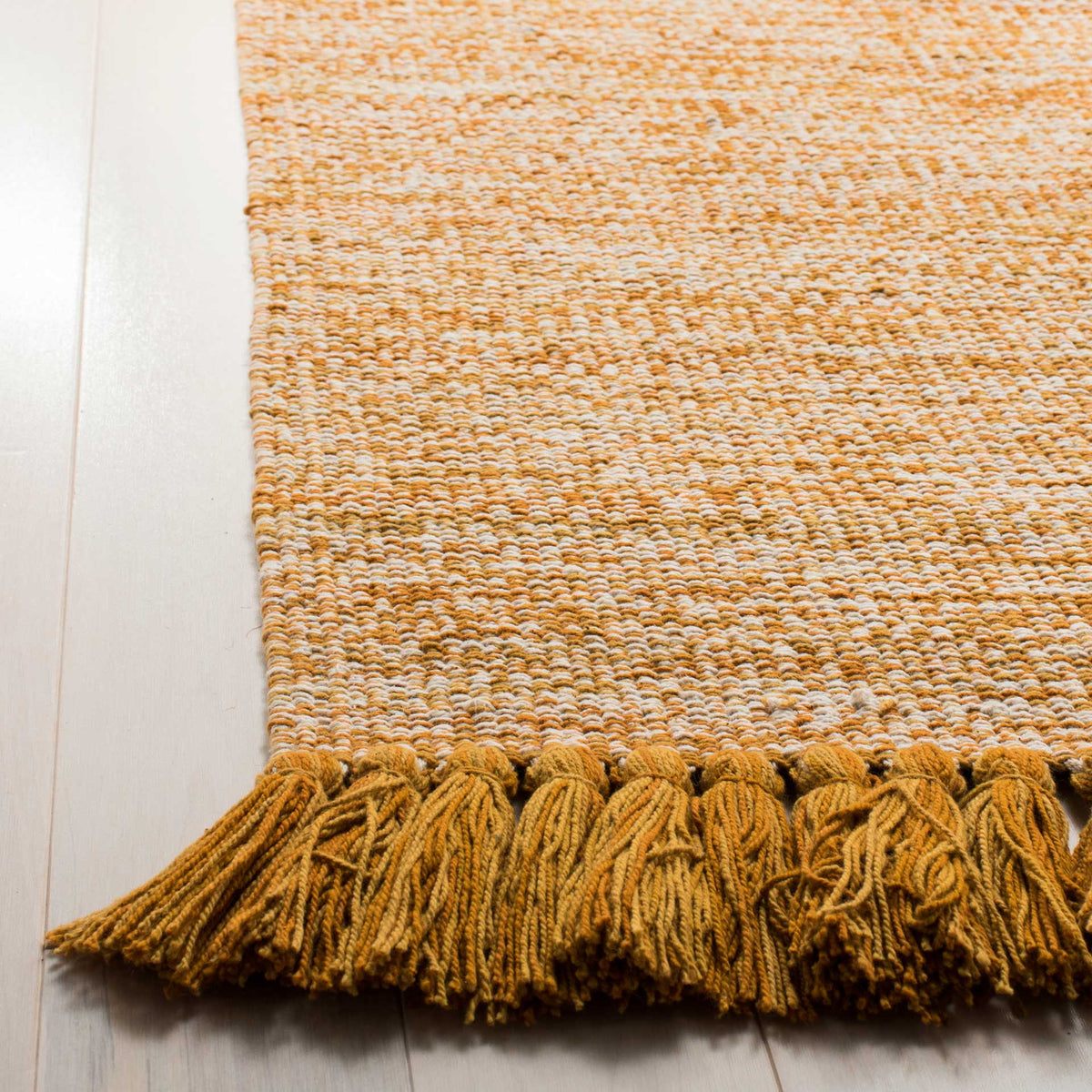 Rich golden tassels frame the textured weave of this gold-and-ivory cotton rug.