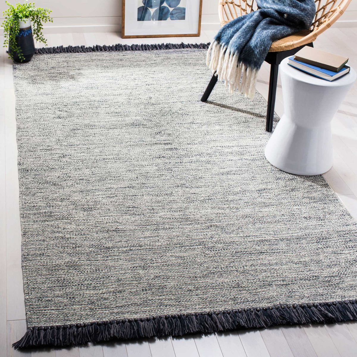A softly textured gray rug adds understated warmth beneath furniture, edged with deep charcoal fringe.