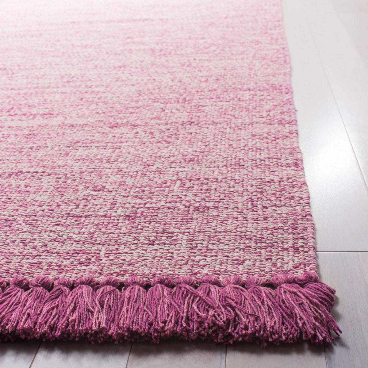 Deep pink fringe highlights the rug's richly textured pink-and-ivory woven surface.