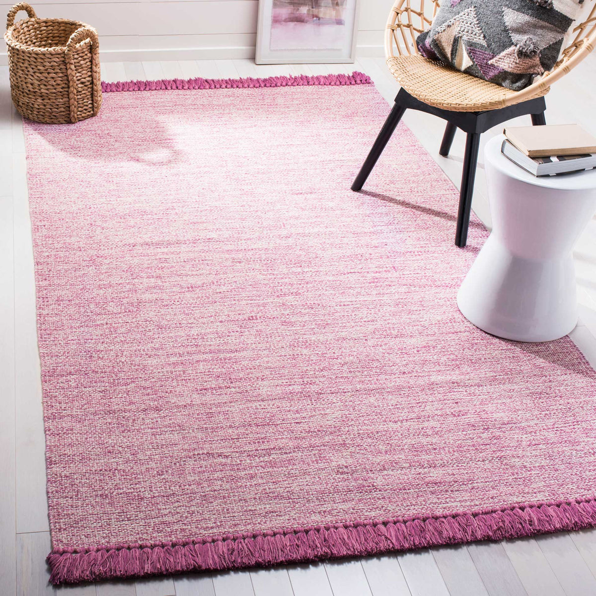 A pink heathered rug brightens the floor with textured color and playful fringed ends.