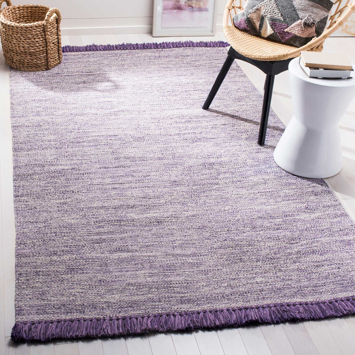 A lavender-and-purple rug creates a soft foundation with a textured weave and tasseled edges.