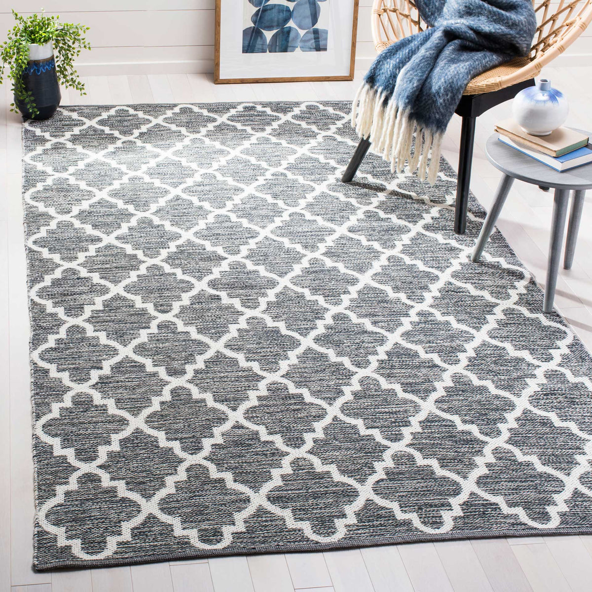 A charcoal and ivory trellis rug anchors a relaxed seating nook with graphic contrast.