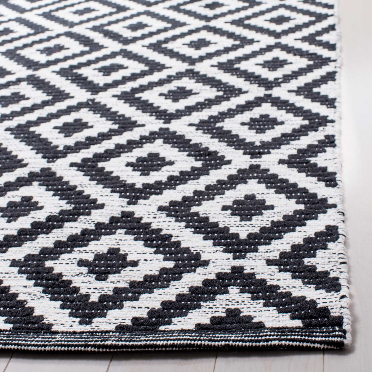Textured black diamonds and a neatly finished edge showcase the rug's woven cotton.