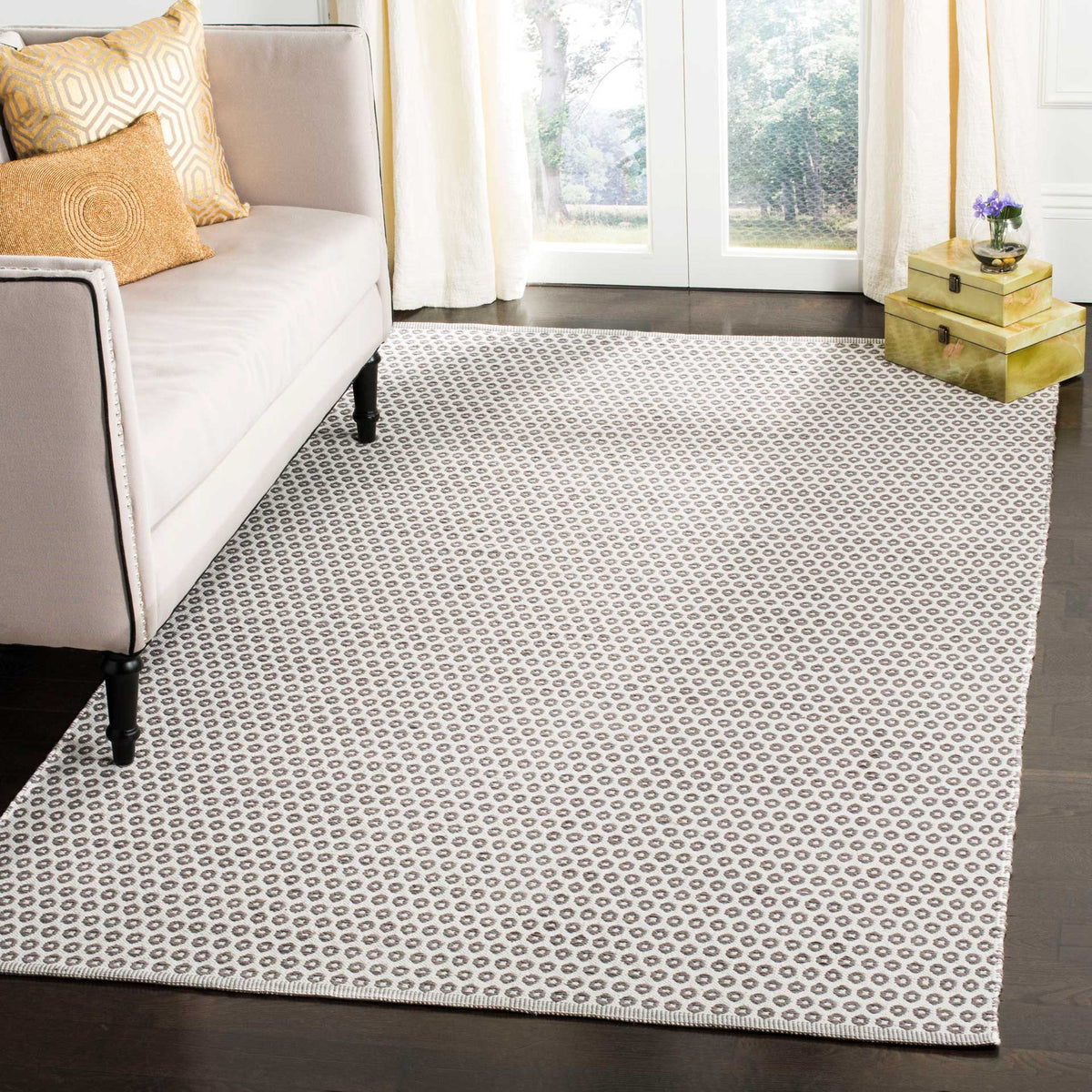 Gray and ivory ring-patterned rug creates a soft, neutral foundation beneath a living room sofa