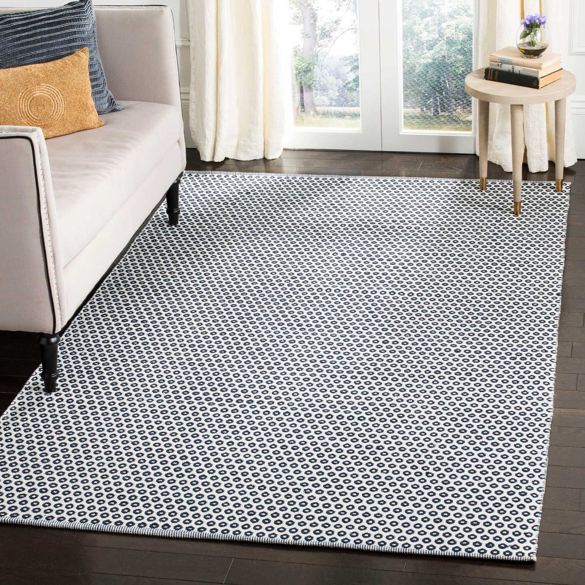 Navy and ivory ring-patterned rug lends graphic contrast to a light, airy living room