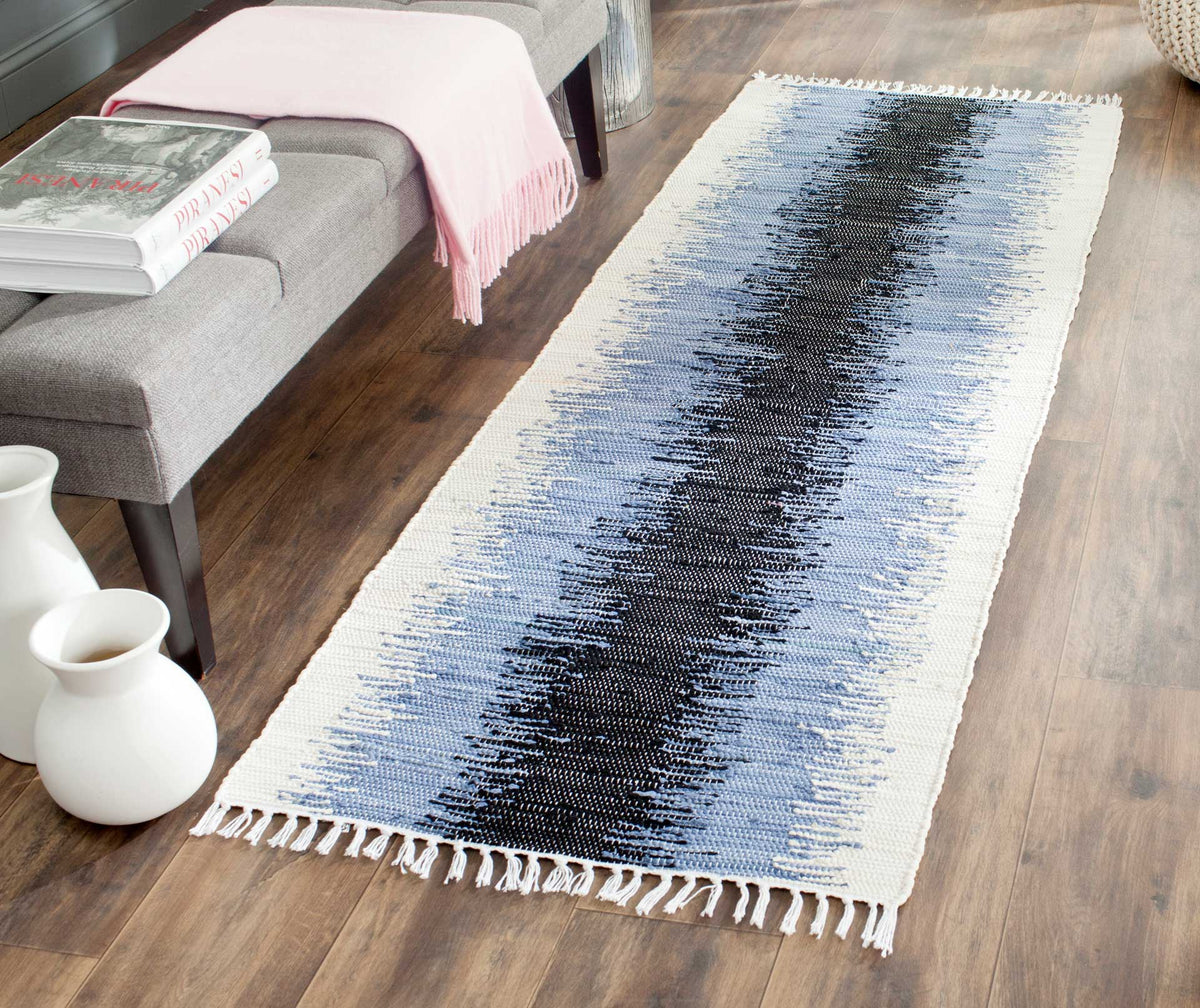 Fringed cotton runner adds a bold black and blue-gray abstract accent to a wood-floored room