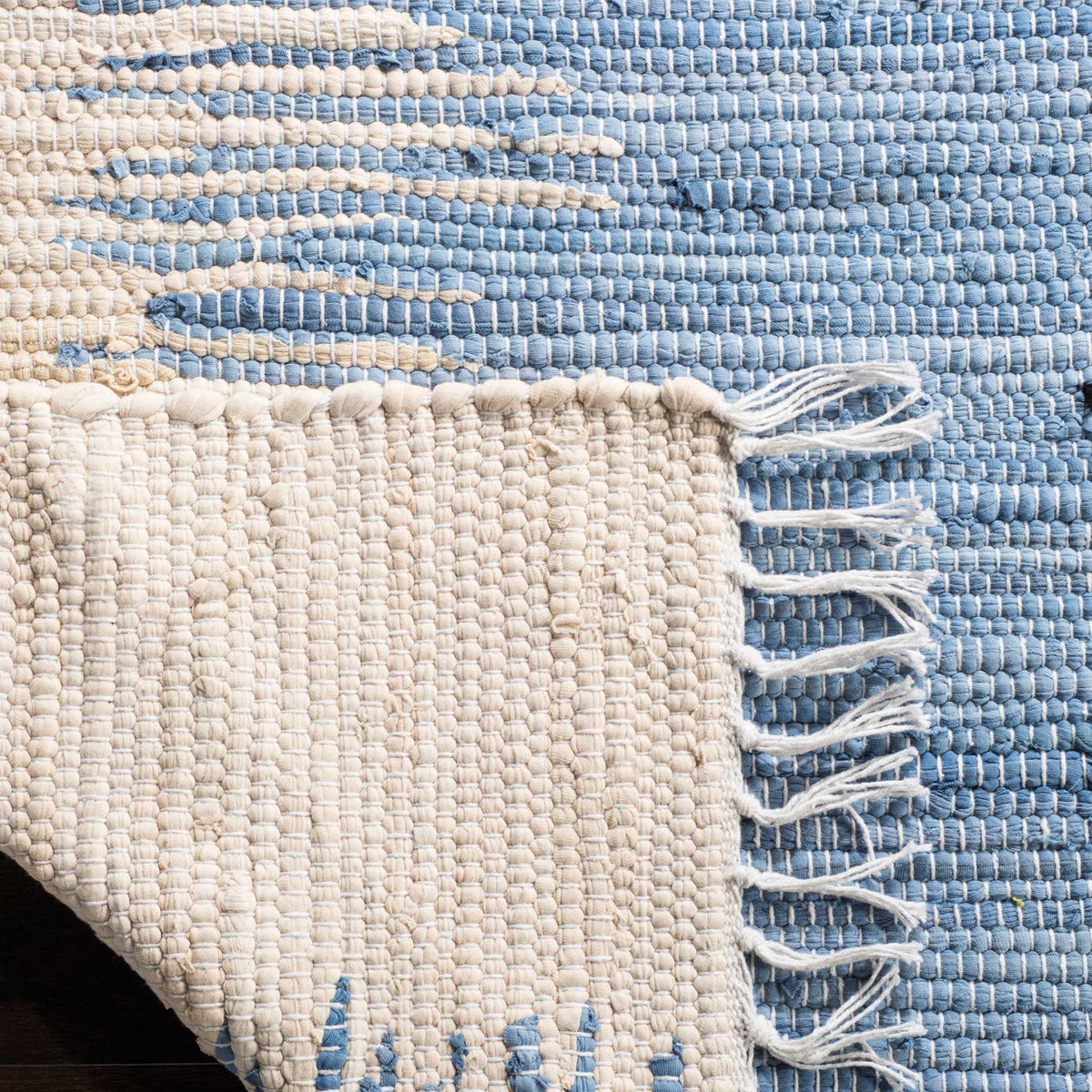 Ivory cotton backing and looped fringe contrast with the rug's blue woven pattern.