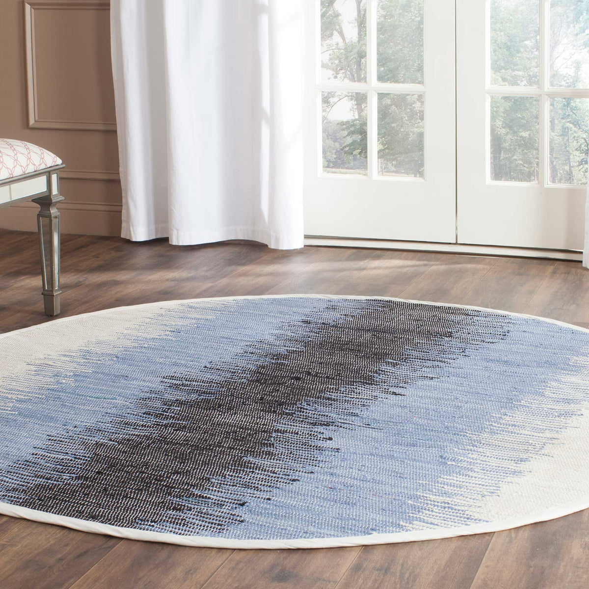 Blue and black abstract bands give this round rug a striking presence on warm wood floors
