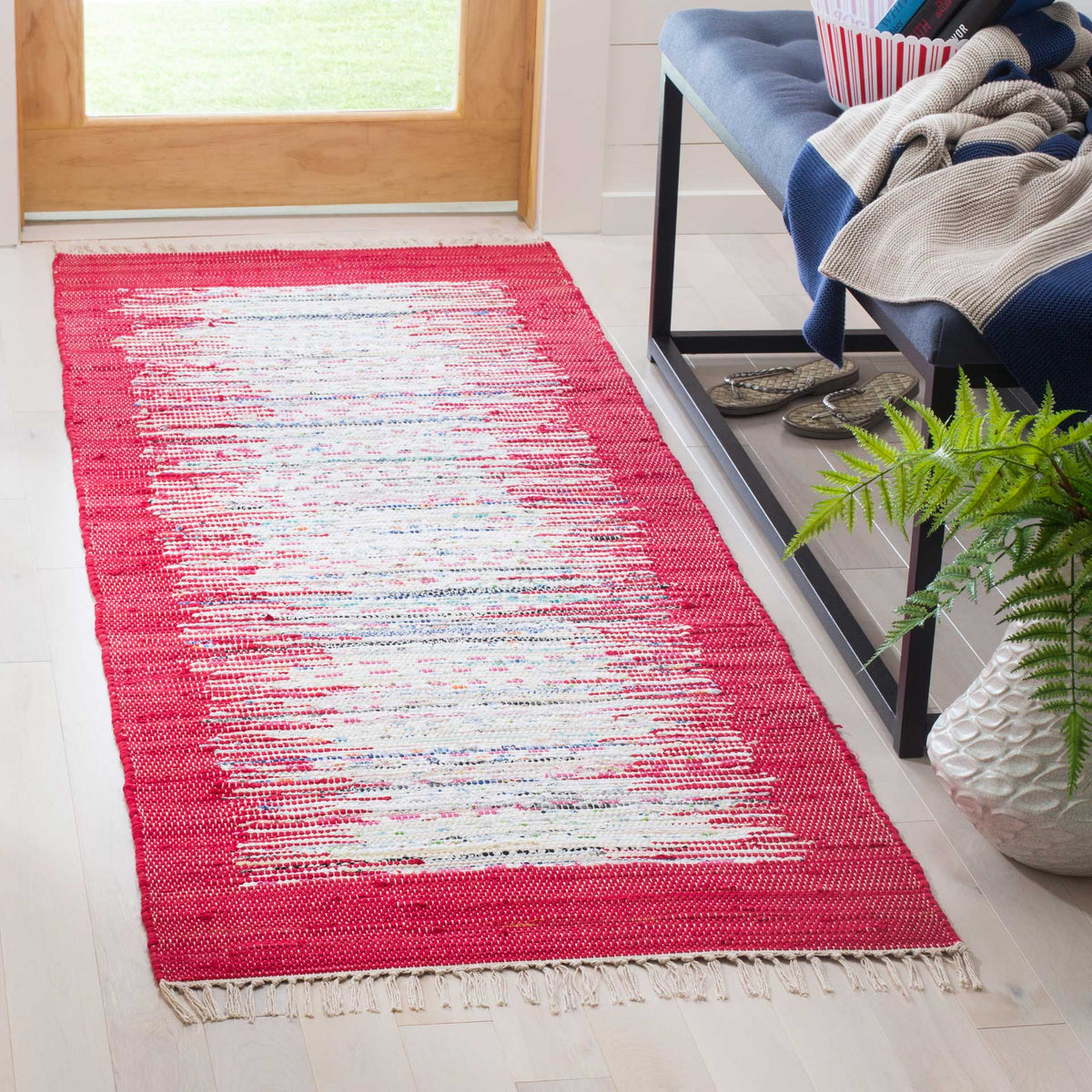 A red and ivory runner brightens an entryway with abstract striations and a soft fringed edge.
