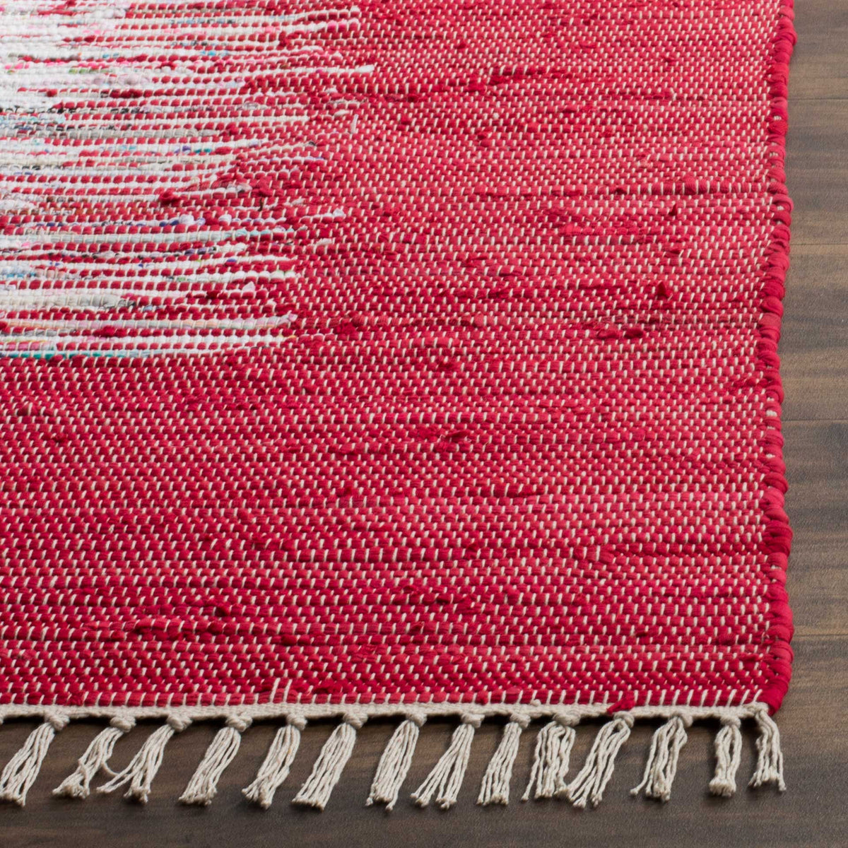 Pale fringe trims a vivid red woven cotton corner, bringing out its tactile yarns and ivory accents.