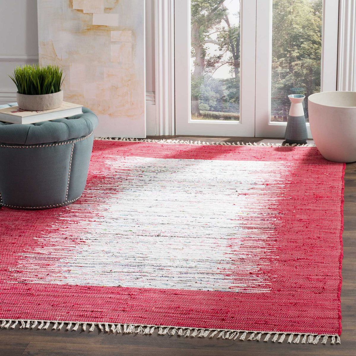 A bright red and ivory rug adds lively contrast and soft woven texture to a sunlit living area.