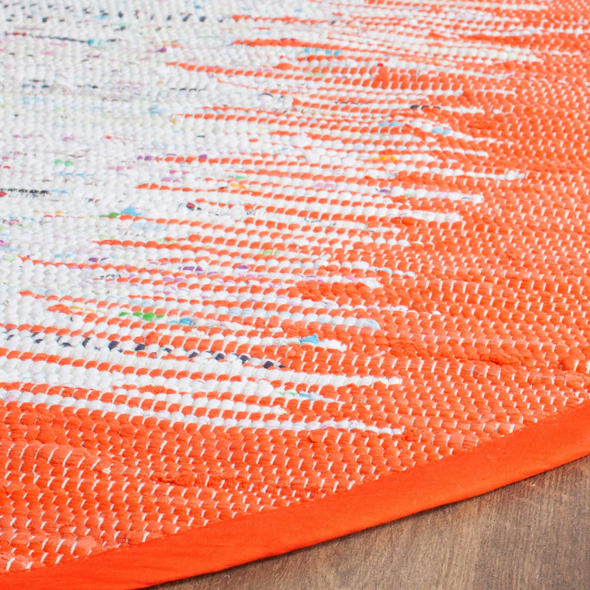 Orange cotton loops blend into a flecked ivory weave above a neatly bound edge